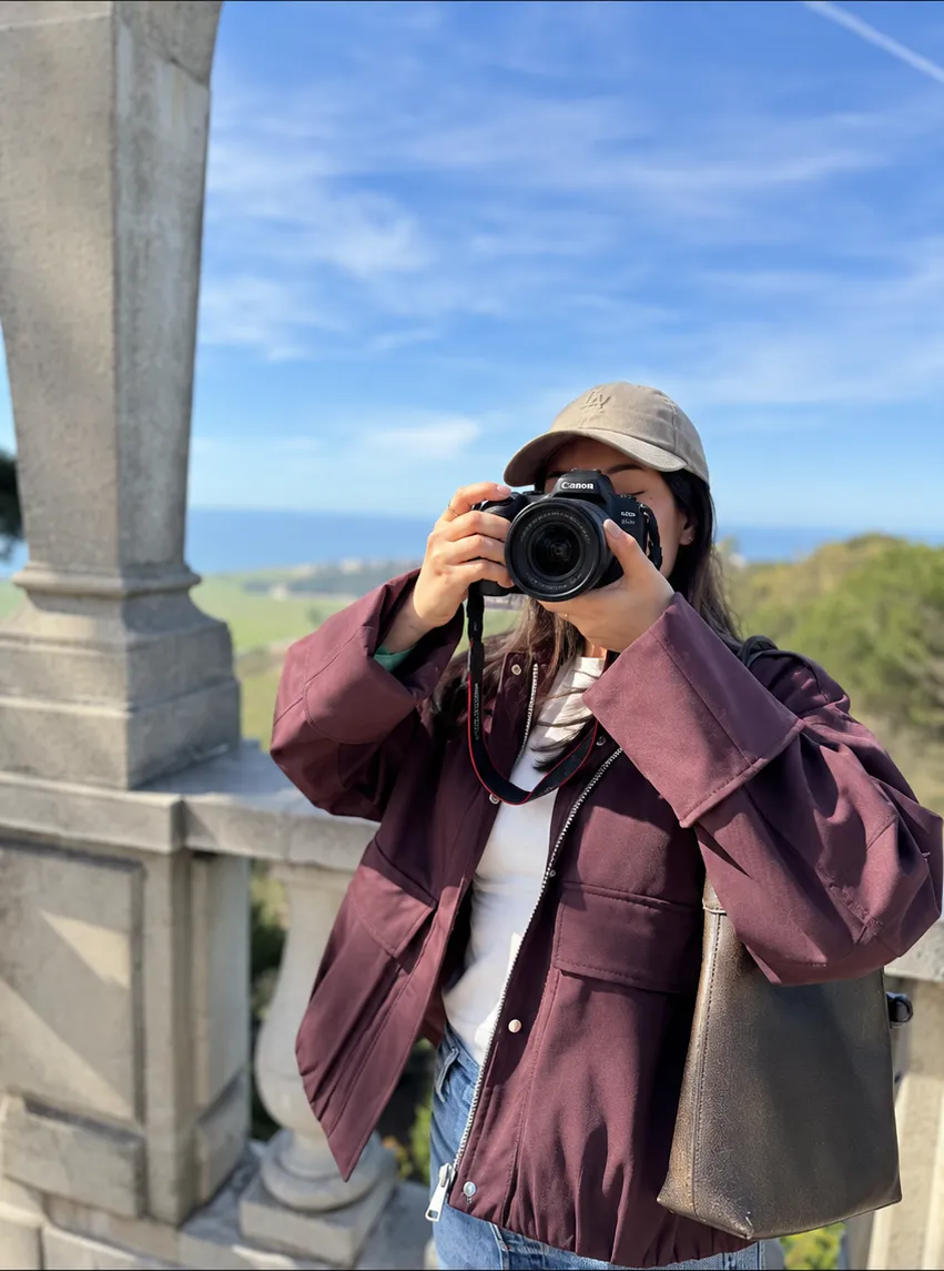 Annalisse Galaviz photographing a coastal view with a Canon camera.